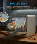 Self Contained Countertop Dishwasher With Built In Water Tank And Gentle Baby Care Mode with soft LED light illuminating dishes.