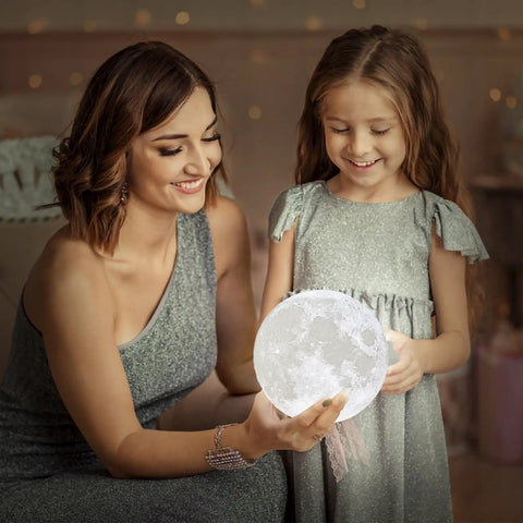 Mother and daughter admiring Moon Lamp 3D Printed Lunar Light With Black Stand 3.5 Inch Night Light USB Charging Touch Control Brightness Dual Warm And Cool White Real Moon Surface Inspired By NASA Photos Great Gift For Kids Women Girls Boy Birthday in a cozy setting.