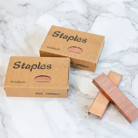 Rose Gold Staples Refill Kit With 7000 Premium 26 By 6 Standard Size Staples, 12mm Width, 7 Box Pack For Most Desk Staplers, Stainless Steel With Rose Gold Plating, Heavy Duty Office Supplies And Accessories. Two boxes of rose gold staples on marble surface.