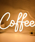 Coffee Neon Light Sign USB Powered Wall Or Table Decor For Home Kitchen Cafe Bar Warm White 11.8 Inch By 6.69 Inch Night Light Mood Builder With Pre Drilled Holes And 6.6 Ft USB Cord displaying in warm white glow on a tabletop