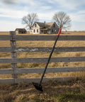Dual Hoe And Rake Garden Tool With 58 Inch Fiberglass Shaft For Cultivating Soil Breaking Up Compact Dirt Leveling Beds And Yard Cleanup Heavy Duty leaning against wooden fence