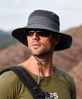 Man wearing Unisex Sun Hat With 360 Degree UV Protection, Wide Brim, Adjustable Chin Strap, Dark Grey, in outdoor setting.