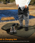 Person using Wader Bag Foldable With Changing Mat And Shoulder Strap For Fishing Travel And Hunting Waterproof Leak Proof Interior With PVC Coating Rugged 600D Ripstop Build And Mesh Boot Storage Built To Last beside a lake.