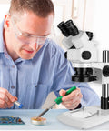 Professional Trinocular Stereo Zoom Microscope With 56 LED Ring Light For Close Up Work 6X To 45X Magnification, WF10X Eyepieces, 0.6X To 4.5X Zoom Objective, 0.5X CTV Trinocular HD Adapter, Camera Ready. technician using trinocular microscope for PCB soldering