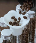 14 Piece Single Dose Coffee Bean Storage Tubes With Airtight One Way Valve And Heavy Duty Metal Stand pouring beans into tube.