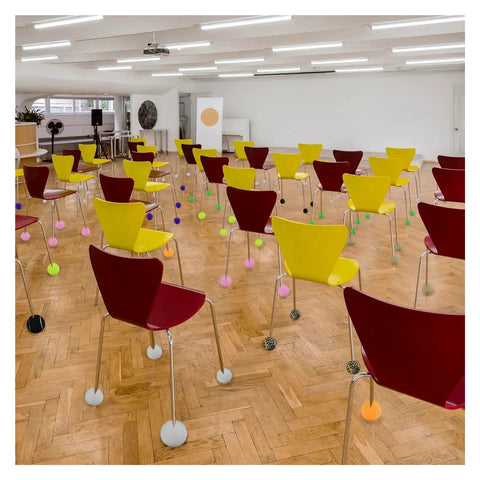 Chairs with colorful tennis ball glides for floor protection in a room showcasing 12 Pack Precut Tennis Ball Glides for Walkers.