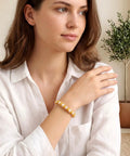 Woman wearing bracelet with Gold Mini Crown Charms 100 Pieces, 3D Vintage Alloy Queen King Crowns Beads, on white blouse background