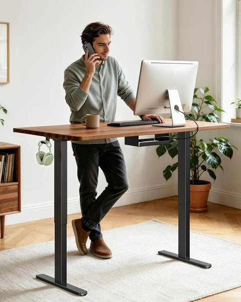 Man using Rock This Dual Motor Standing Desk Frame For 44 To 90 Inch Desktops, Holds Up To 264 Lbs with coffee.
