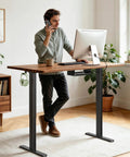 Man talking on phone while standing at Marsail Dual Motor Electric Standing Desk Frame in stylish home office setup.