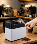 Automatic Electric Portafilter Cleaner For Coffee Grounds Handles Espresso Pucks With Zero Sweat Easy Drop Off Knock Box in cafe setting.