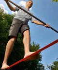 Man balancing on 65ft Ninja Slackline Kit With Ratchet System And Tree Protectors, 500lb Capacity Backyard Set