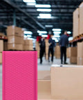 Hot Pink 8.5 X 12 Inch Bubble Mailers Dope Self Seal Padded Envelopes in a warehouse setting with focus on texture and size