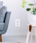 Ultra Durable Shatterproof Outlet Wall Plates 1 Gang Duplex Covers 12 Pack White Polycarbonate Thermoplastic UL Listed Heat And Fade Resistant Premium Receptacle Wall Plate With Color Matched Screws installed in living room wall next to sofa and plant