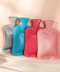 Four colored rubber hot water bottles lined up, with ribbed exteriors for heat retention. Premium Classic Rubber Hot Water Bottle Red For Cozy.
