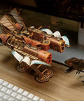3D Wooden Steampunk Spaceship Puzzle Kit for Adults with Mortise Tenon Joinery, displayed near keyboard and monitor