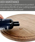 Hand applying No Mineral Oil Cutting Board Oil And Wax For Wooden Surfaces, Food Grade Conditioner with bottle on wooden board.