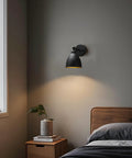 Industrial Hardwire Wall Sconce With Old School Farmhouse Vibe in bedroom, black finish, installed above nightstand, soft light
