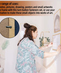 Metal picture frame hardware kit used to hang gold-framed wall art; woman mounting frames.