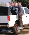 Man using Heavy Duty Tire Step For Trucks And SUVs, 300 Lb Capacity, Non Slip Cheese Grater Steel Surface, to reach roof rack