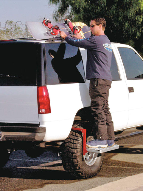Man using Heavy Duty Tire Step For Trucks And SUVs, 300 Lb Capacity, Non Slip Cheese Grater Steel Surface, to reach roof rack