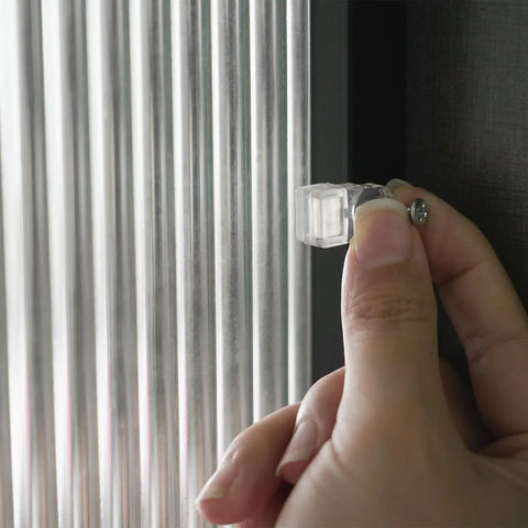 Hand installing a clear glass retainer clip from the Real Deal 25 Pack Glass Retainer Clips With Screws For Cabinets Windows Doors And Mirrors.