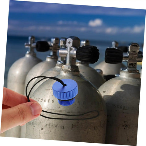 Hand holding blue dive tank valve accessory scuba valve protector cap beside tanks on the beach, emphasizing durability and easy install.
