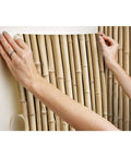 Hands applying Brown Bamboo Peel And Stick Wallpaper Roll For Easy Removable Wall Decor, Self Adhesive Repositionable Covering.