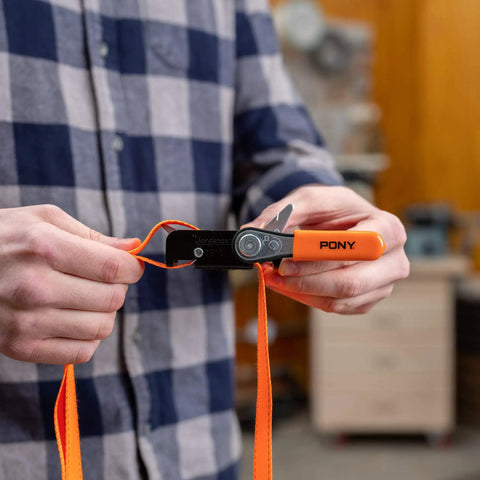 Person holding a Heavy-Duty Adjustable Band Clamp For Woodworking And Framing, 15-Foot Strap, Self-Locking Ratcheting Handle
