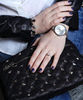 Black quilted leather handbag with silver pyramid studs; close-up view.