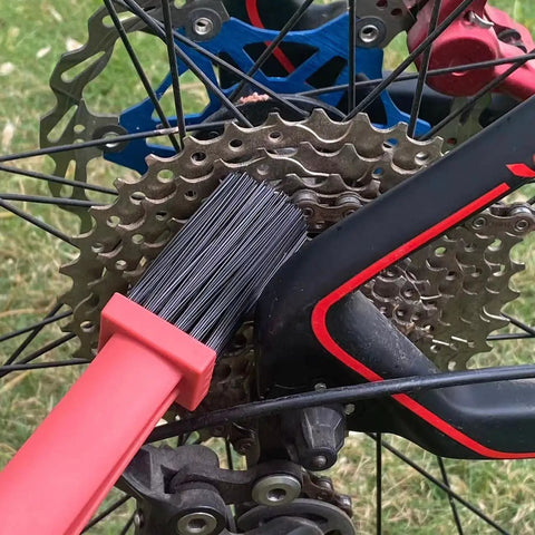 Bike Chain Cleaning Tool Set With Crankset Brush And Motorcycle Chain Cleaner Brushes against bicycle gears, plastic body in black and red