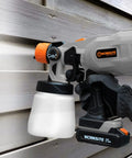 Cordless 20V Paint Sprayer Gun With Dual Batteries, HVLP Sprayer against wooden wall, adjustable valve knob visible