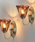 Vintage Glass Wall Sconces Set of 2,Aged Brass Bathroom Vanity Lighting with amber flower glass shades on wall.