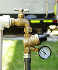 Brass RVGUARD water pressure regulator valve with gauge and inlet screen, installed on an RV water line.