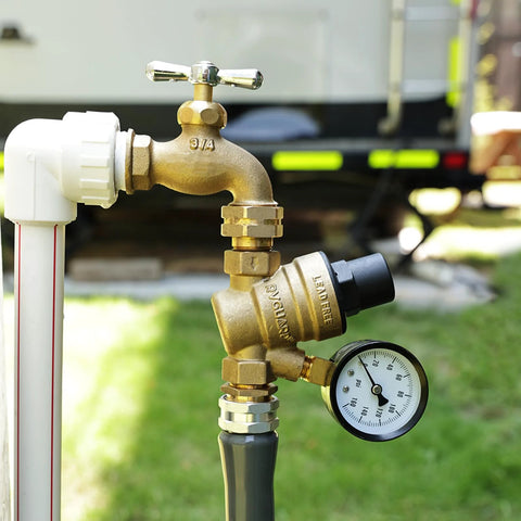 Brass RVGUARD water pressure regulator valve with gauge and inlet screen, installed on an RV water line.
