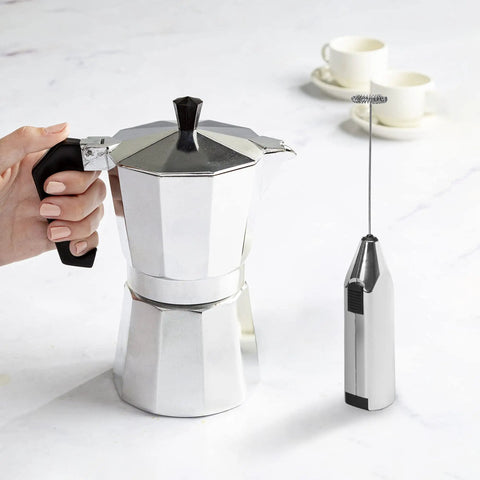 Compact Stovetop Espresso Maker And Handheld Electric Milk Frother Gift Set Pro Grade Aluminum Moka Pot with battery frother in hand.
