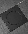 Drop Down Square Pop Up Floor Drain With Matte Black Chrome Cap and Odor Locking Grille For Bathrooms installed in floor, flush with tiles.