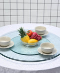 Heavy Duty Tempered Glass Lazy Susan Turntable Silky Smooth Rotating Serving Platter with fruits and bowls on dining table.
