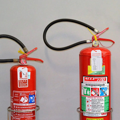 Two fire extinguishers with attached tags, suitable for 50 Pack Fire Extinguisher Tags With Adjustable Wire Ties 4 Point 2 By 2 Point 1 Inches.