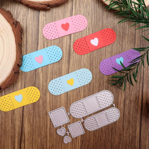 Colorful plasters with heart designs next to a metal cutting die set on a wooden surface
