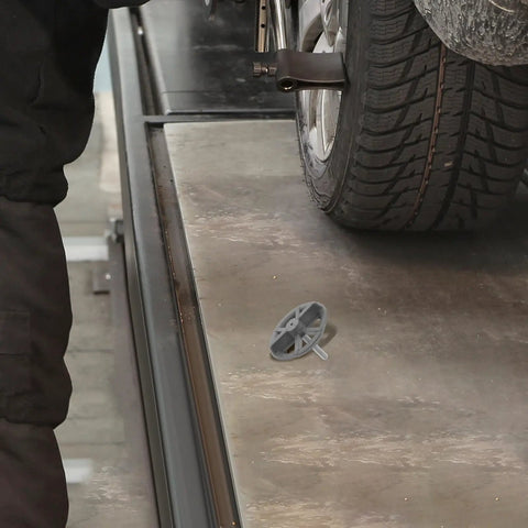 Spare Tire Bolt Adapter And Hold Down Retainer Kit For Kia Forte shown on garage floor near vehicle wheel.