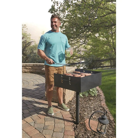 Man grilling sausages on Heavy Duty Park Style Charcoal BBQ Grill For Camping Backyard Patios And Tailgating in the sun.