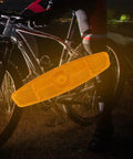 Four Pack Bike Spoke Reflectors For Night Riding Safety Bright Universal Fit Easy Install Wheel Lights For Mountain And Road Bikes 4.53 X 1.06 Inches White attached to a bike wheel.
