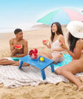 Ultralight Aluminum Mini Table With Adjustable Retractable Legs on beach, 66 lb capacity, used for picnic with watermelon and fruits.