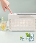 Fast Freeze Mini Countertop Ice Maker Features A Clear Viewing Lid While You Watch Crisp White Cubes Drop Right Out on a table.