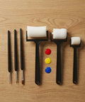 Six Piece Foam Sponge Roller And Brush Kit With Solid Comfort Grip Handles For Smooth Watercolor Flow Graffiti Touchups And Simple DIY Art Crafting Projects arranged on wood with paint.