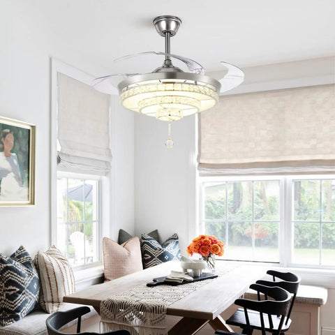Crystal Ceiling Fan With Lights Retractable Fandelier in modern chrome installed above a dining table in a bright room.