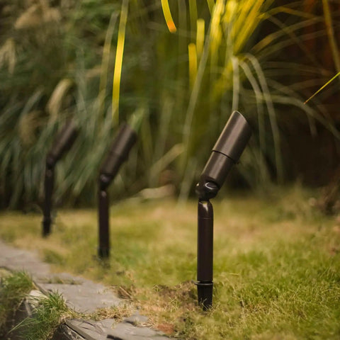 Low Voltage Landscape Spotlight Kit 8 Pack, 20W Halogen Outdoor Lights illuminating garden pathway, metal stakes visible
