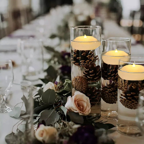 Pack Of 4 Wax Flickering LED Floating Candles 3 Inch Tealights Waterproof Warm White Battery Operated Flameless Candles For Dope Centerpieces Weddings Pool Parties Decor in glass vase with pinecones on an elegant table setting.