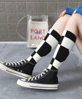 Black And White Piano Grid Thigh High Socks Unisex Breathable Moisture Wicking Crew Socks For Women Men displayed with black sneakers.
