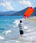 Person flying Hydra II Closed Cell Foil Water Trainer Kite 3.5m for Easy Water Relaunch on a beach with hills in background